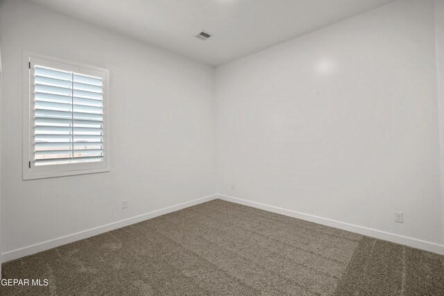 carpeted spare room with visible vents and baseboards