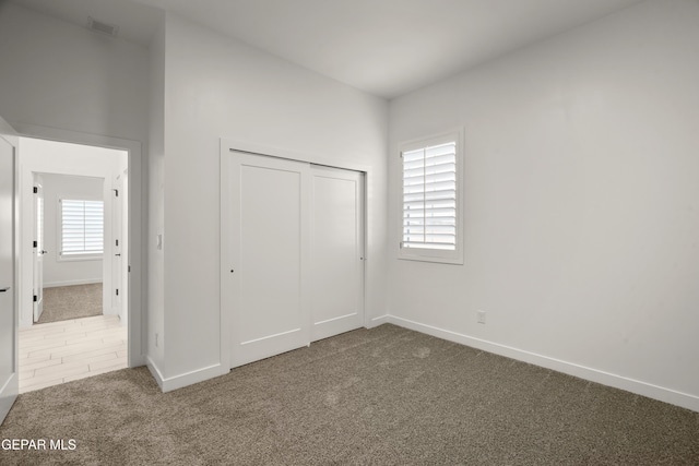 unfurnished bedroom featuring visible vents, multiple windows, baseboards, and carpet floors