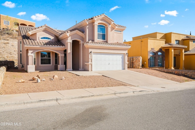 mediterranean / spanish home featuring stucco siding, concrete driveway, an attached garage, and a tiled roof