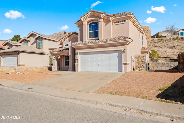 mediterranean / spanish-style house featuring stucco siding, an attached garage, and a tile roof