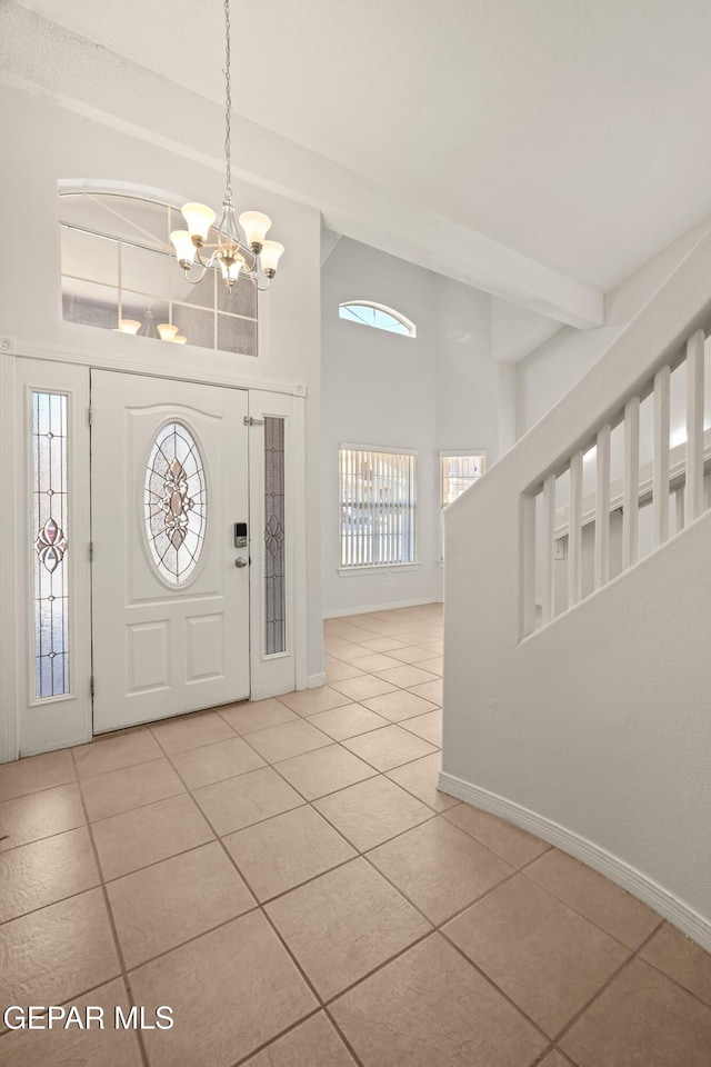 foyer entrance with baseboards, high vaulted ceiling, an inviting chandelier, beam ceiling, and light tile patterned flooring