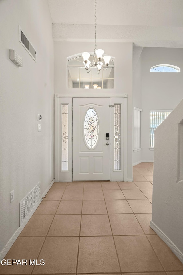 entryway with visible vents, a chandelier, and a towering ceiling