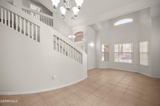 interior space featuring an inviting chandelier, a high ceiling, baseboards, and tile patterned floors