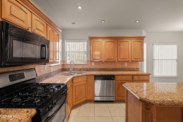 kitchen featuring light stone counters, light tile patterned floors, recessed lighting, a sink, and appliances with stainless steel finishes