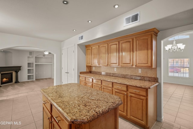 kitchen with light tile patterned flooring, visible vents, arched walkways, and light stone counters