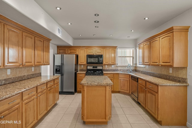 kitchen featuring visible vents, a sink, a kitchen island, appliances with stainless steel finishes, and light stone countertops