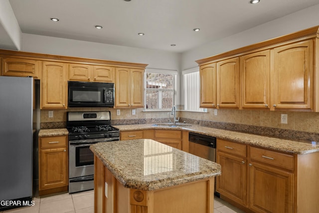 kitchen with light stone countertops, a sink, stainless steel appliances, backsplash, and a center island