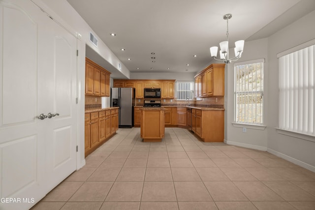 kitchen featuring light tile patterned floors, visible vents, a kitchen island, an inviting chandelier, and appliances with stainless steel finishes