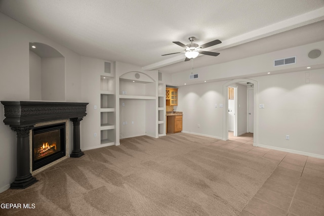 unfurnished living room featuring arched walkways, visible vents, a ceiling fan, and a glass covered fireplace