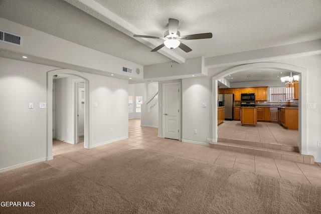 unfurnished living room featuring visible vents, light carpet, light tile patterned floors, ceiling fan with notable chandelier, and arched walkways