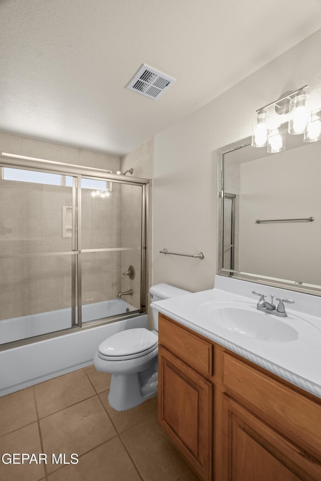 full bathroom with vanity, visible vents, bath / shower combo with glass door, tile patterned flooring, and toilet