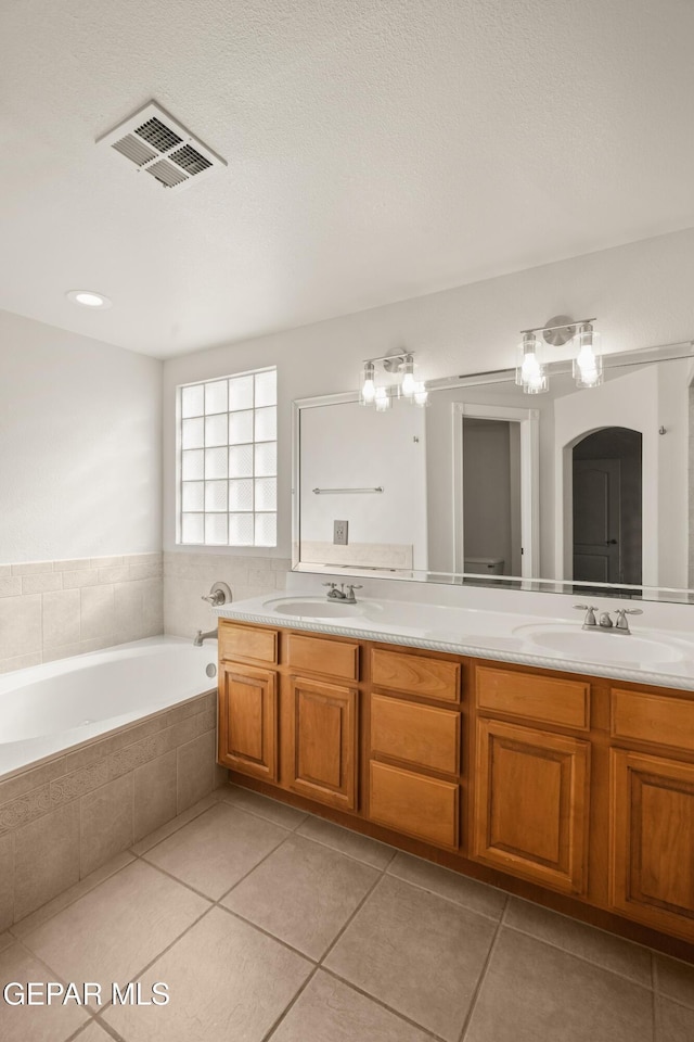 bathroom with a sink, visible vents, a bath, and double vanity