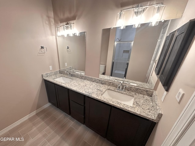 bathroom with a sink, baseboards, toilet, and a stall shower