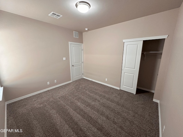 unfurnished bedroom featuring a closet, baseboards, visible vents, and dark colored carpet