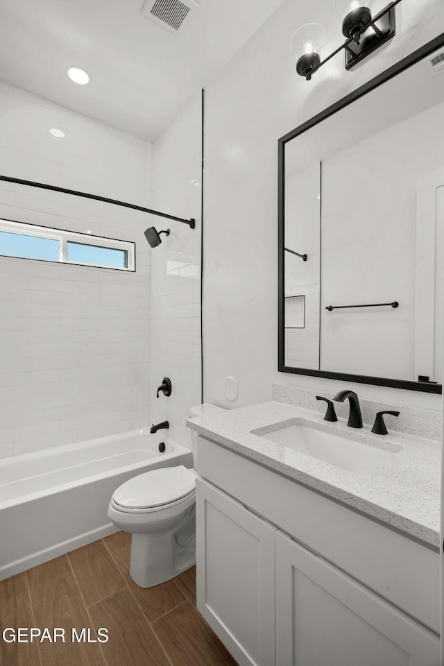 full bathroom featuring wood finish floors, visible vents, toilet, shower / bath combination, and vanity