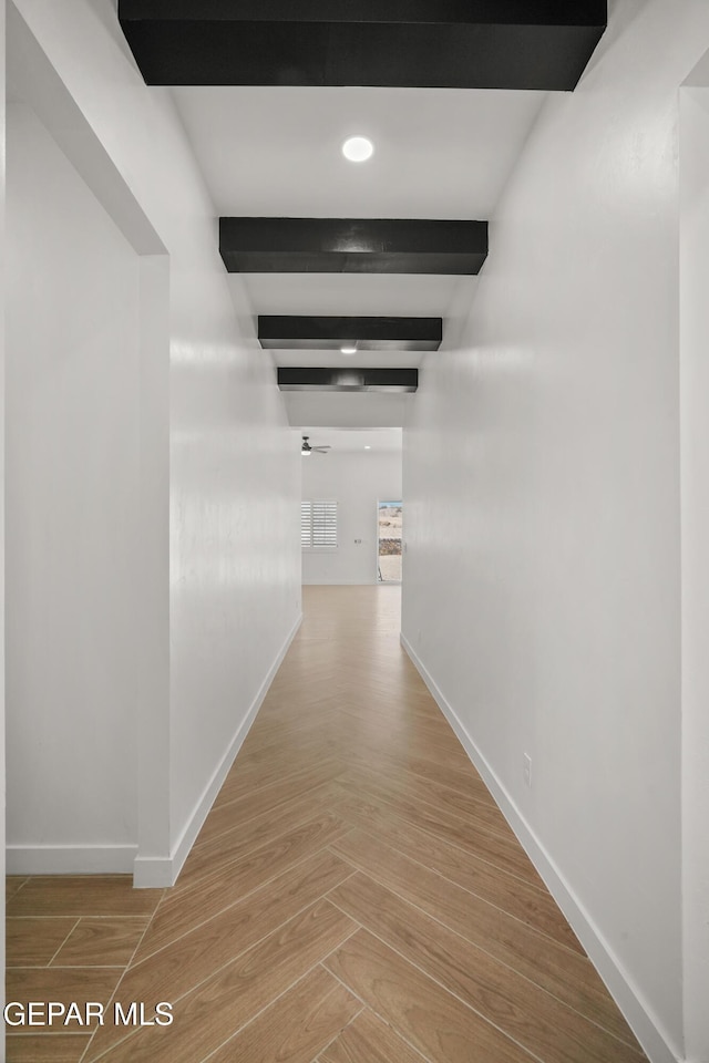 corridor featuring beamed ceiling and baseboards