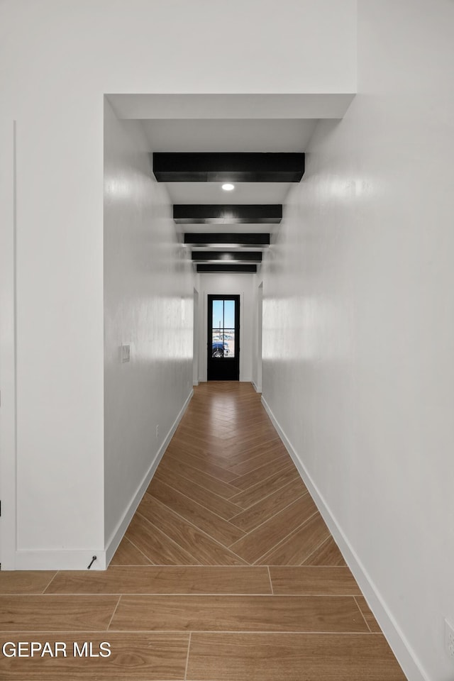 hallway with beamed ceiling, baseboards, and wood tiled floor