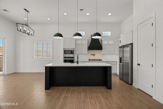 kitchen featuring visible vents, light wood-style flooring, custom range hood, stainless steel appliances, and light countertops