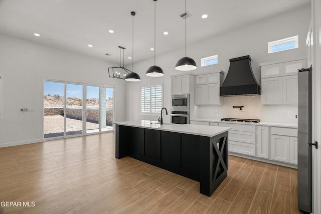 kitchen with premium range hood, light wood-type flooring, appliances with stainless steel finishes, light countertops, and decorative backsplash