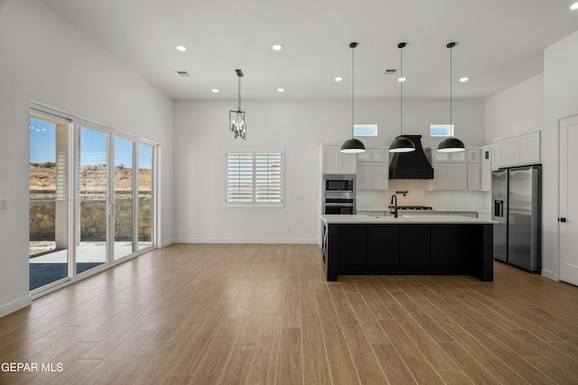 kitchen with stainless steel appliances, light wood finished floors, a high ceiling, and light countertops