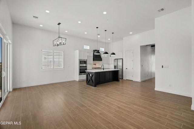 kitchen featuring stainless steel appliances, light wood-style floors, open floor plan, and light countertops