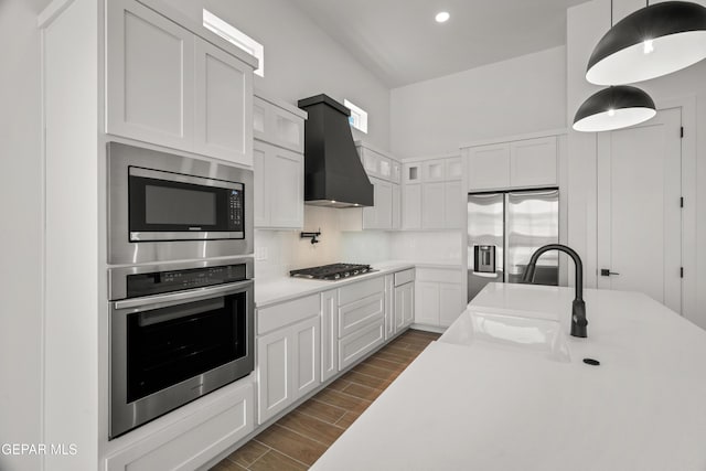 kitchen featuring backsplash, wood finish floors, light countertops, stainless steel appliances, and wall chimney exhaust hood