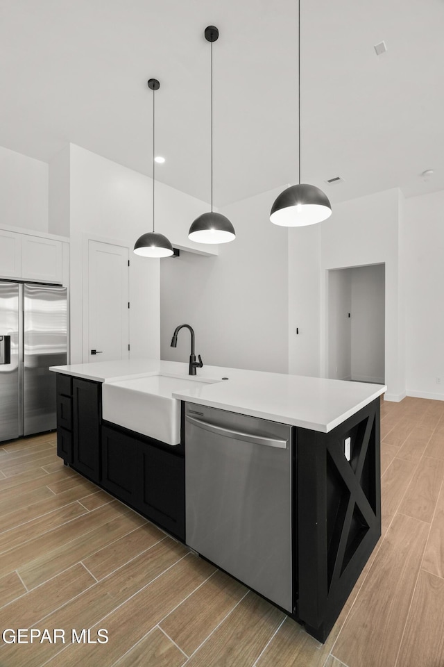 kitchen featuring a sink, wood tiled floor, light countertops, and stainless steel appliances