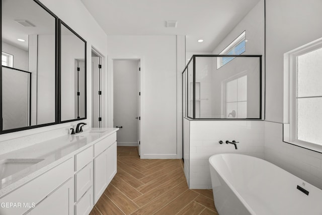 full bathroom with a stall shower, a sink, recessed lighting, double vanity, and a soaking tub