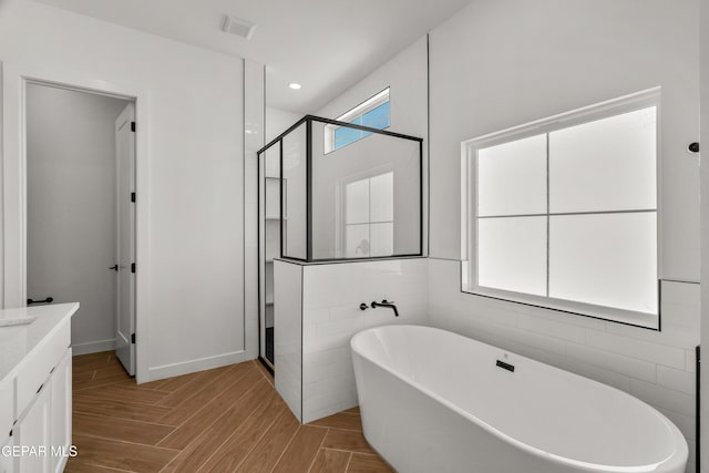 full bath with visible vents, recessed lighting, a stall shower, a freestanding tub, and vanity