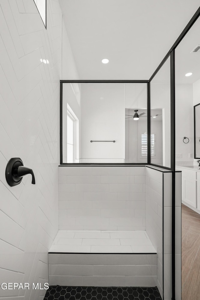 bathroom with visible vents, ceiling fan, vanity, and a tile shower