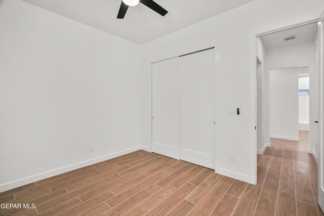 unfurnished bedroom featuring a closet, a ceiling fan, baseboards, and wood tiled floor