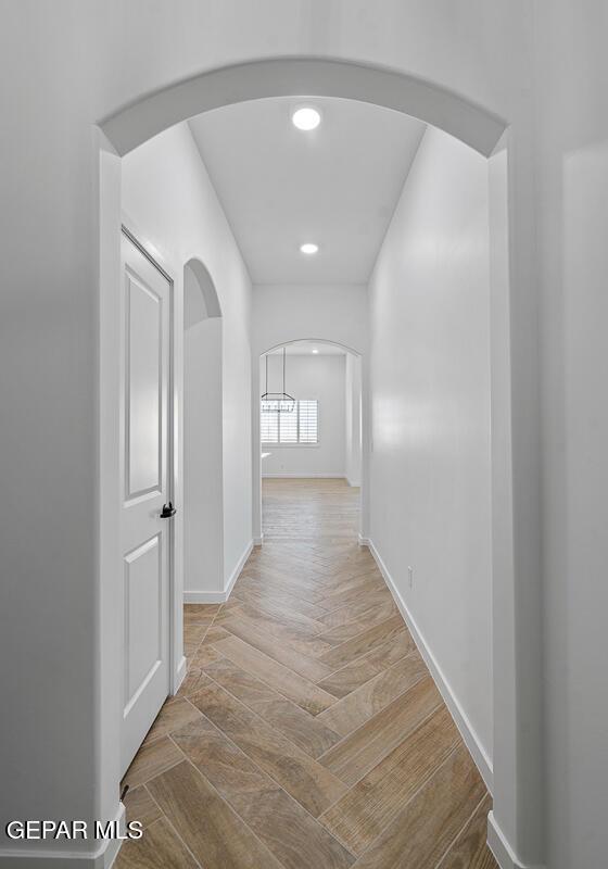 hall with recessed lighting, wood finished floors, arched walkways, and baseboards