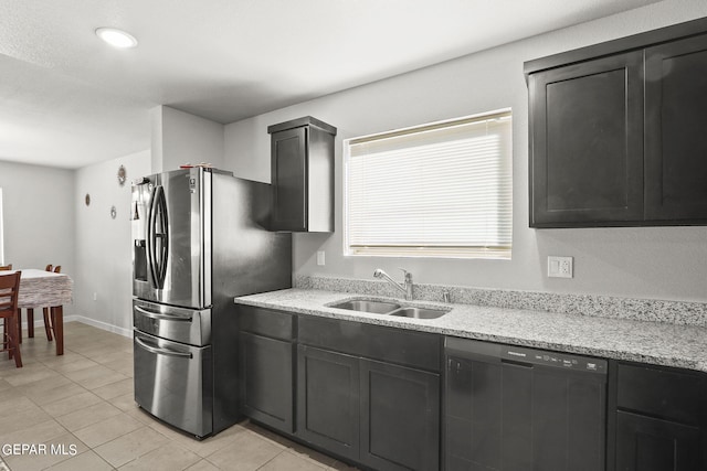 kitchen featuring dark cabinetry, light tile patterned floors, a sink, stainless steel refrigerator with ice dispenser, and dishwasher