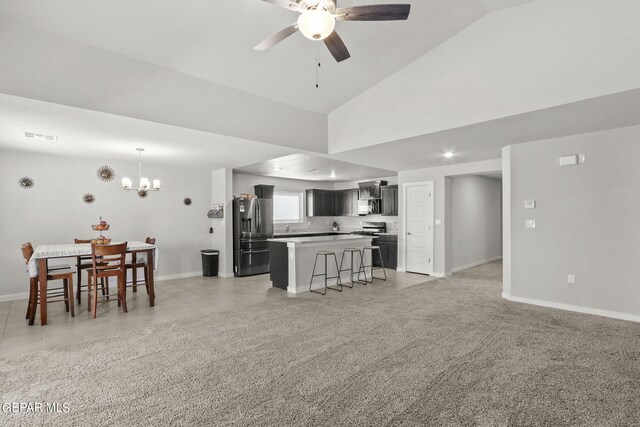 living area featuring ceiling fan with notable chandelier, light colored carpet, and baseboards