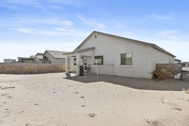 rear view of house with stucco siding and fence