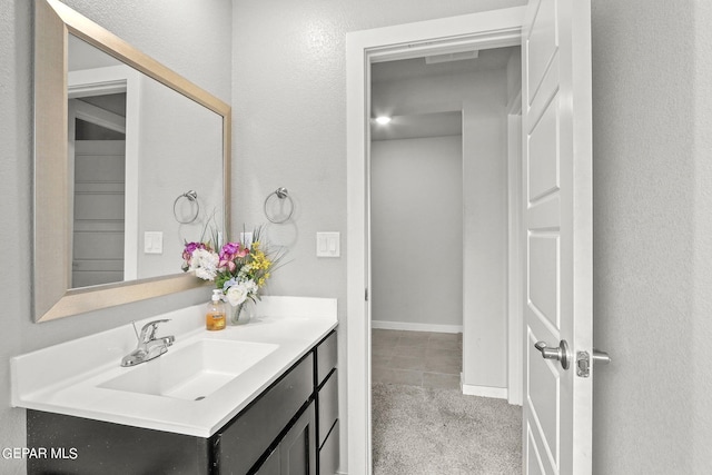 bathroom featuring vanity, a textured wall, and baseboards