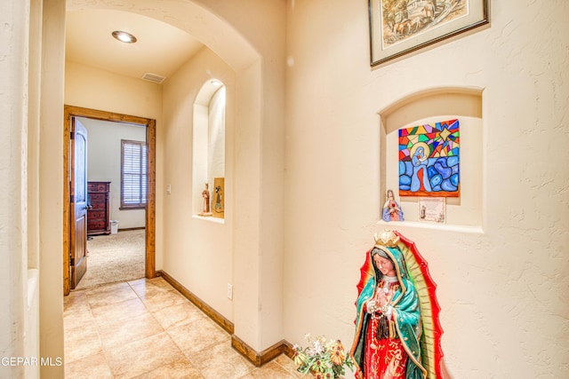 hallway with baseboards, visible vents, and arched walkways