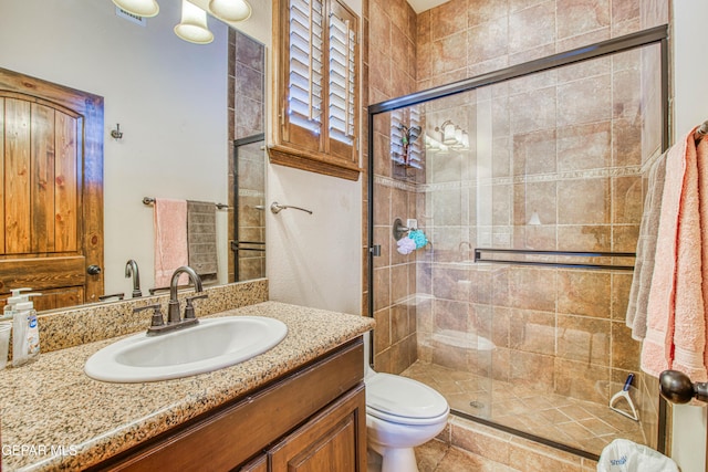 bathroom featuring a shower stall, toilet, and vanity