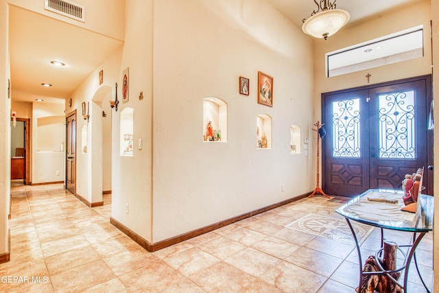 entryway featuring visible vents, french doors, arched walkways, a high ceiling, and baseboards