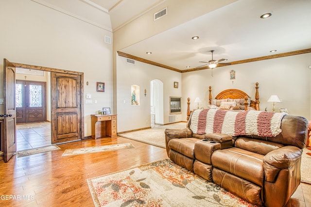 bedroom featuring arched walkways, visible vents, light wood finished floors, and ornamental molding