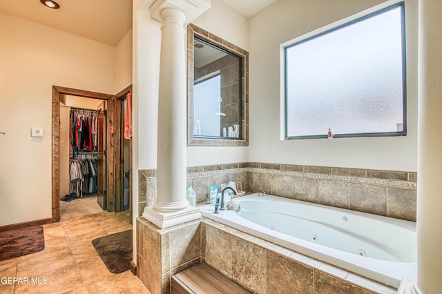 full bath featuring tile patterned flooring, a jetted tub, a walk in closet, and ornate columns