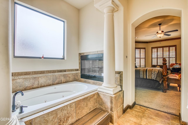 ensuite bathroom featuring a ceiling fan, connected bathroom, a tub with jets, crown molding, and decorative columns