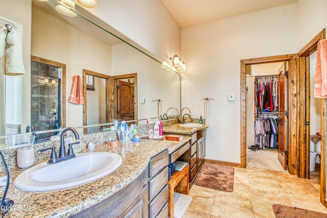 full bath featuring double vanity, a stall shower, a walk in closet, and a sink