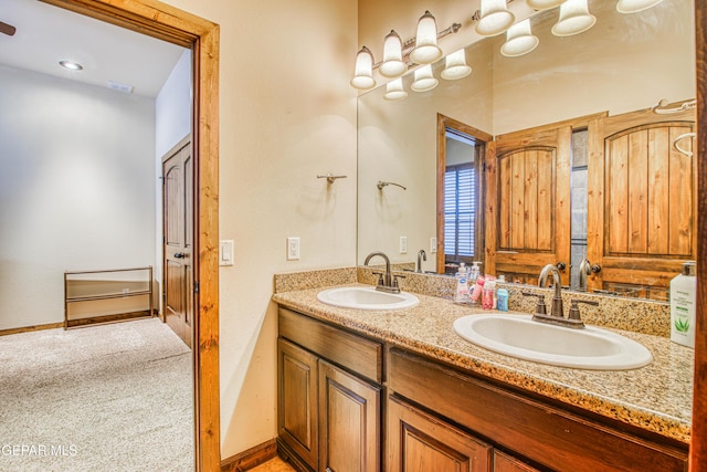 full bath with double vanity, baseboards, and a sink