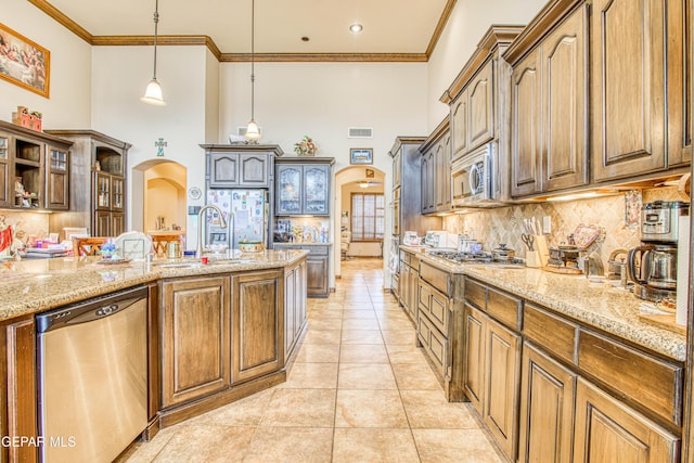 kitchen with visible vents, arched walkways, ornamental molding, a sink, and appliances with stainless steel finishes