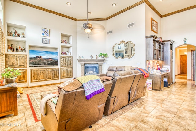 living room with visible vents, built in shelves, arched walkways, and ceiling fan