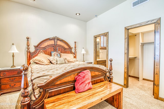 bedroom featuring visible vents, a walk in closet, light colored carpet, ensuite bathroom, and a closet