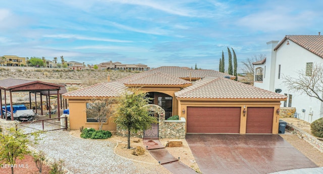 mediterranean / spanish-style home with stucco siding, driveway, an attached garage, and a gate