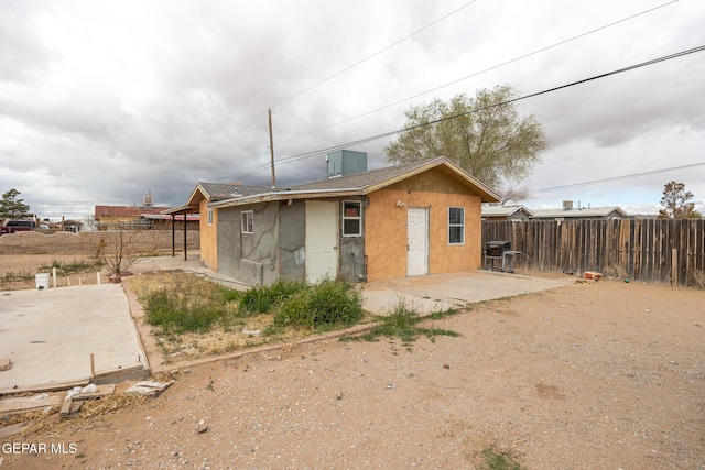 rear view of house with a patio area, fence, and stucco siding