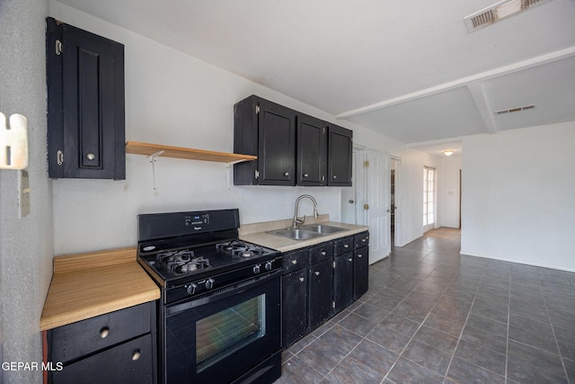 kitchen with black gas stove, light countertops, dark cabinets, and a sink